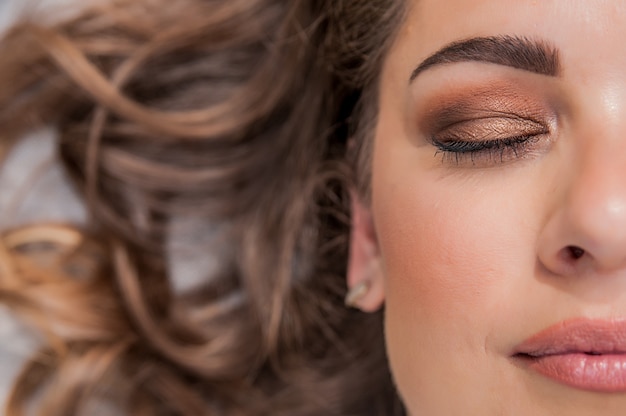 Foto gratuita modello donna sensuale con vento spazzato volare i capelli bruna su sfondo grigio chiaro. acconciatura lunga brillante di salute. bellezza e cura dei capelli. trucco naturale di moda