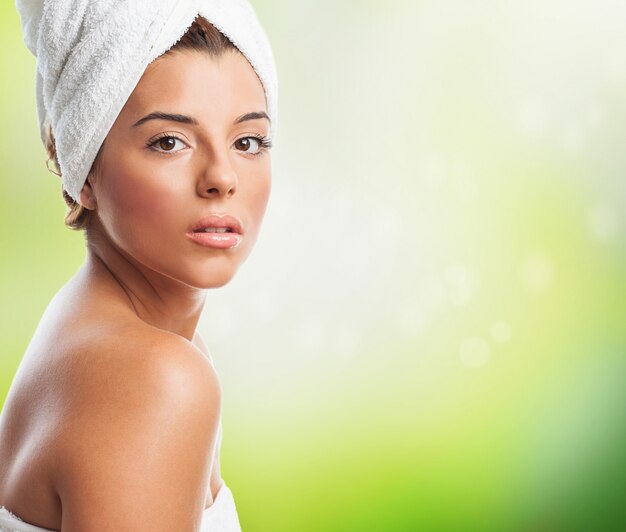 Sensual woman in towel against green background.