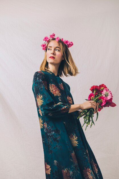 Sensual woman with wreath on head and bouquet of flowers