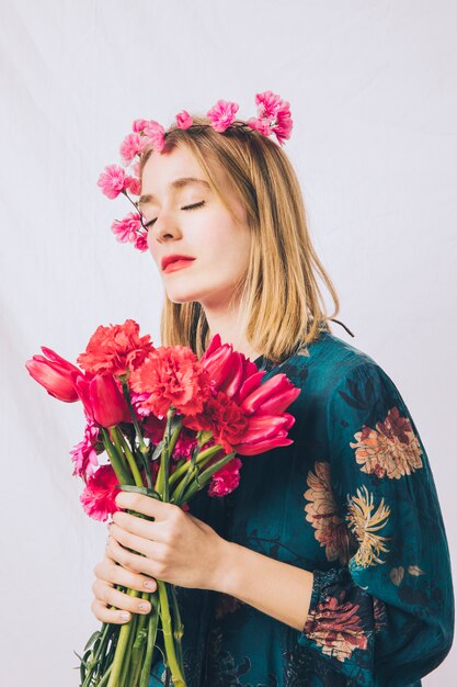 Sensual woman with wreath on head and bouquet of flowers