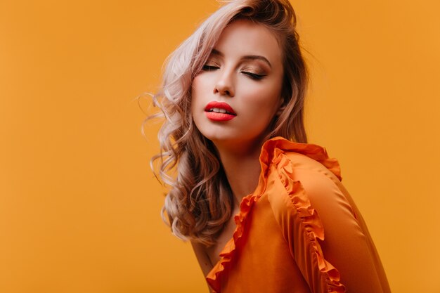 Sensual young woman in bright outfit posing with eyes closed