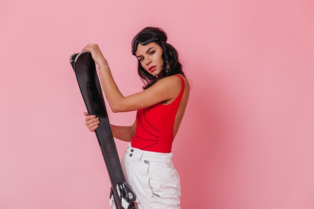 Sensual young woman holding skis