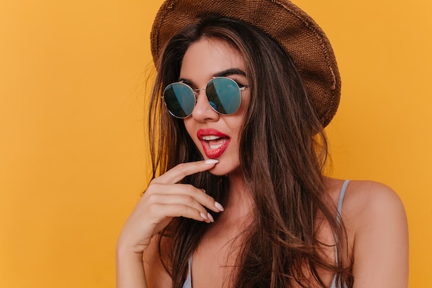 Sensual young woman with bright lipstick playfully posing on orange space