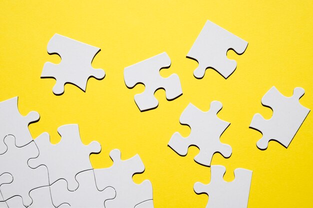 Separate white puzzle piece on yellow backdrop