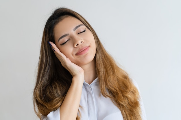 Serene pretty woman making sleep gesture with her eyes closed