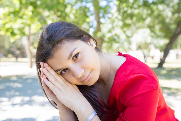 Serene pretty young woman relaxing and posing at camera in park