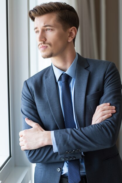 Serious Adult Businessman Looking through Window