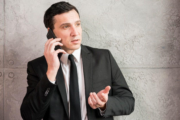 Серьезный взрослый бизнесмен говорит по телефону