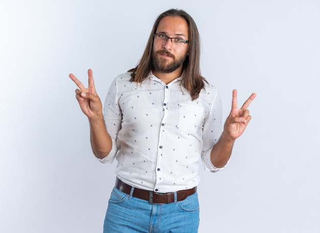Free photo serious adult handsome man wearing glasses doing peace sign