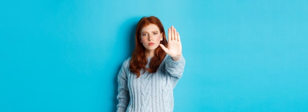 無料写真 真剣で自信に満ちた赤毛の女の子は、行動を禁止するために伸ばした手のひらを見せないように言うのをやめるように言っています
