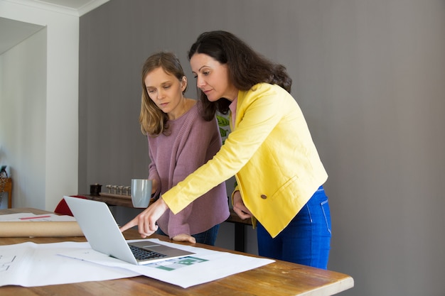 Free photo serious architect showing house design on laptop screen