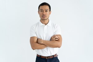 Серьезный азиатский бизнесмен в белой футболке смотря камеру