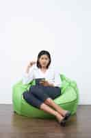 Free photo serious asian businesswoman with sitting on beanbag