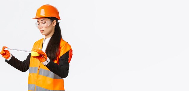 Serious asian female construction engineer technician inspect layout measuring something looking at