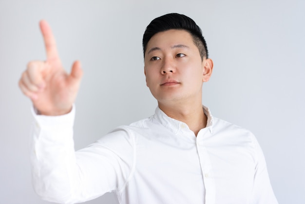 Serious Asian guy touching invisible wall