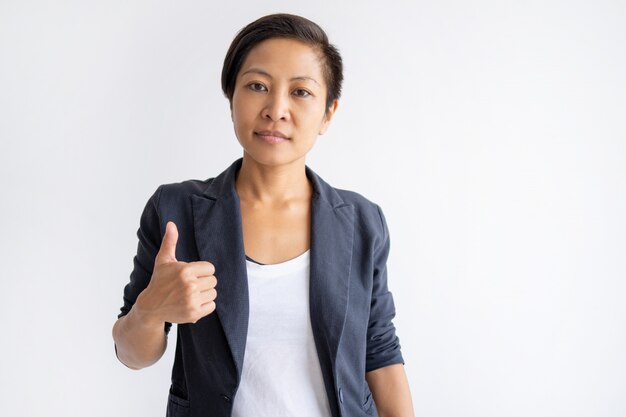 Serious Asian woman showing thumb up