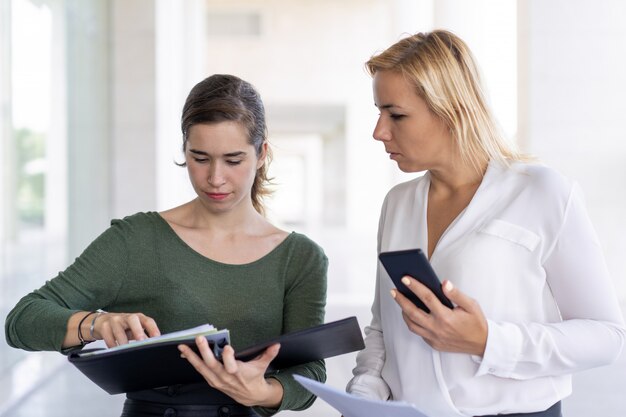 Serious assistant getting out documents from folder