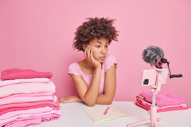 免费照片严重关注花女自由职业者手表视频如何在家洗坐在桌子折叠洗衣孤立的粉红色