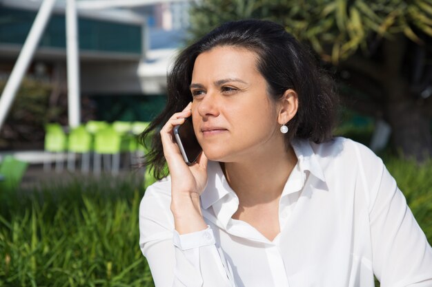 屋外の携帯電話で話している深刻な魅力的な女性