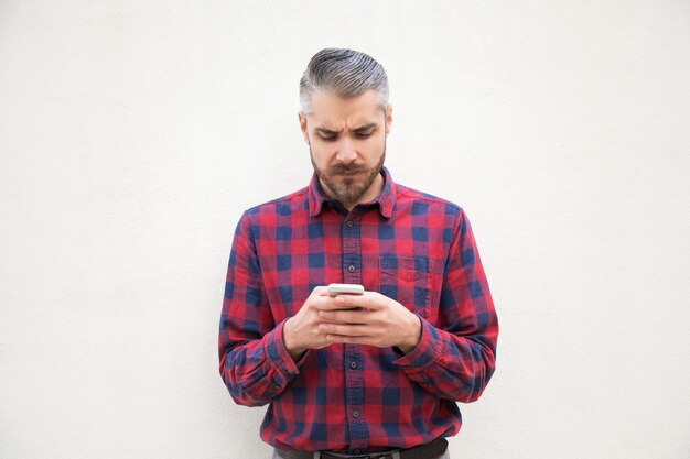 Serious bearded man using cell phone