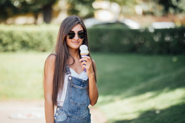 심각한 아름다운 소녀는 하얀 치아로 미소 짓고 아이스크림을 보유하고 있습니다.
