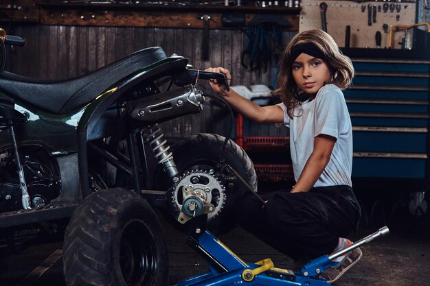 Serious beautiful girl want to be an auto technician when she grows up, she is trying to fix broken ATV.