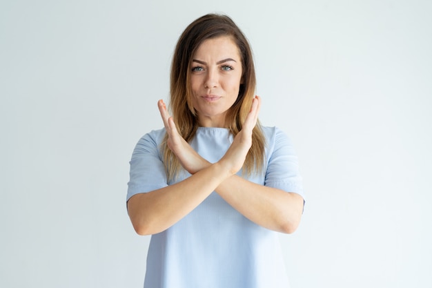 Serious beautiful woman showing crossed hands and looking at camera.