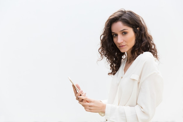 Serious beautiful woman with smartphone looking