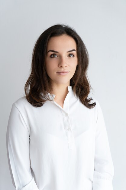 Serious beautiful young woman looking at camera. Lady wearing white shirt and posing.