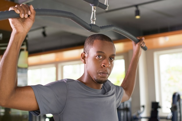 Serious black man exercising on lat pull down machine
