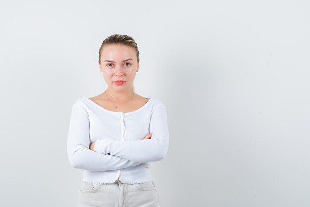 The serious blonde girl is posing for camera on white background