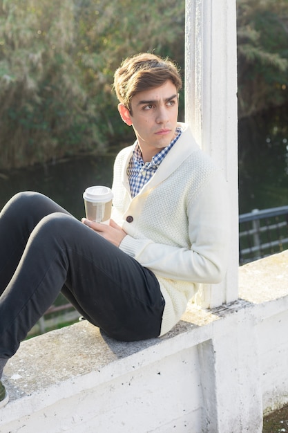 Free photo serious boy posing with a hot coffee