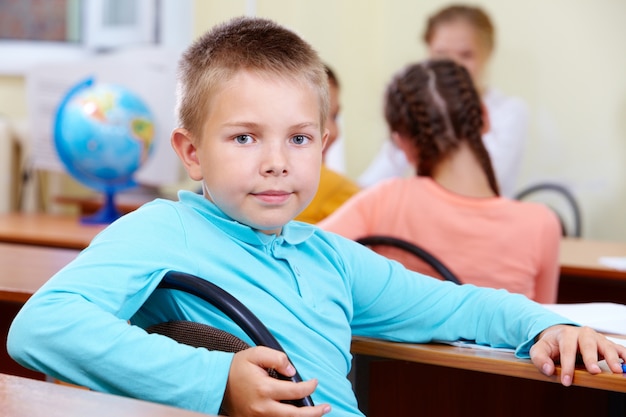 Serious boy with schoolgirl on background