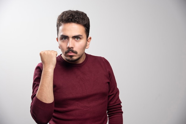 A serious brunette man showing his fist and posing .