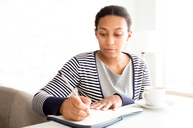 Serious business lady making notes in organizer