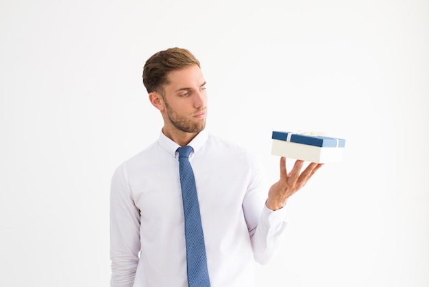 Serious business leader holding gift box with ribbon bow