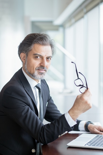 Free photo serious business leader sitting at office desk