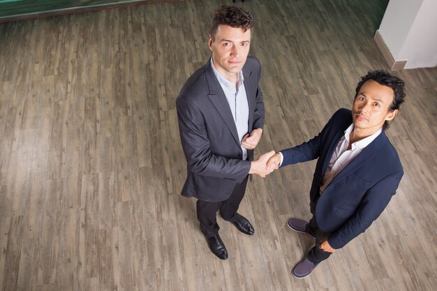 Serious Business Men Shaking Hands in Office Hall