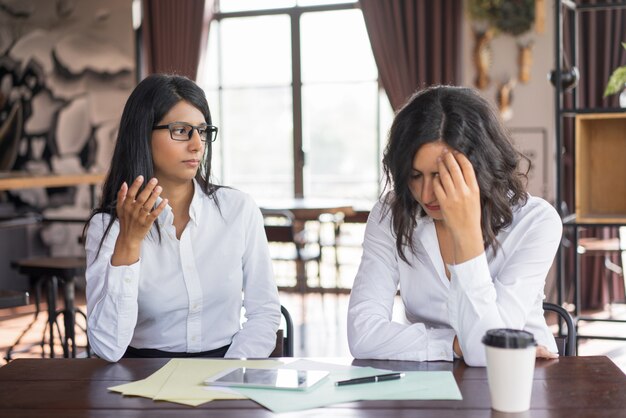 Serious business woman accusing colleague of making mistake. 