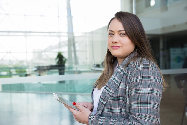 Serious business woman holding tablet outdoors