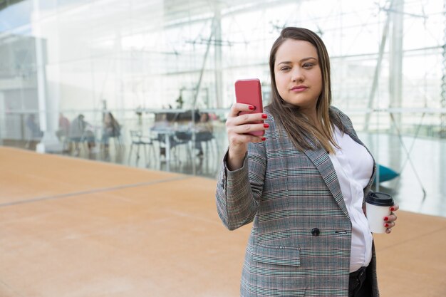 Serious business woman taking selfie photo on phone outdoors