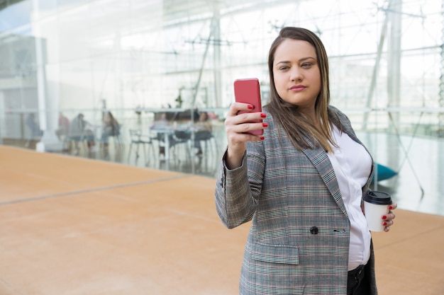 屋外の電話でselfie写真を撮る深刻なビジネス女性