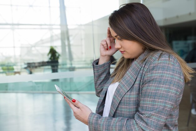 深刻なビジネスの女性を考えて屋外でタブレットを使用して