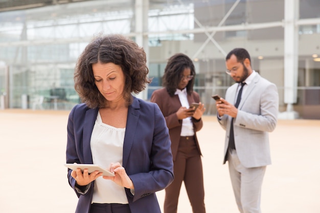 Serious business woman using tablet outside