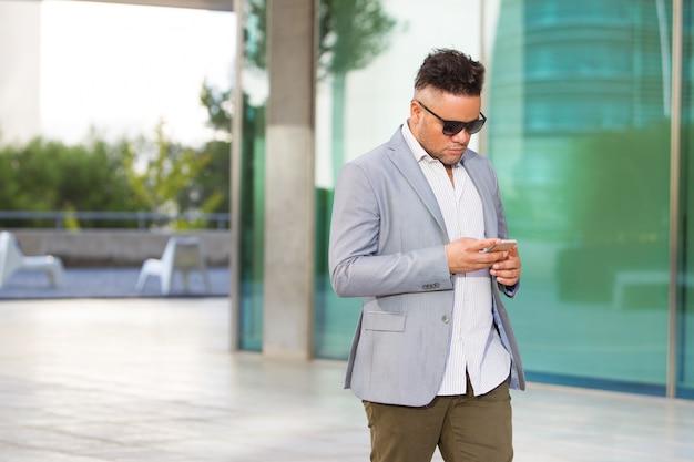 Serious businessman answering sms on smartphone