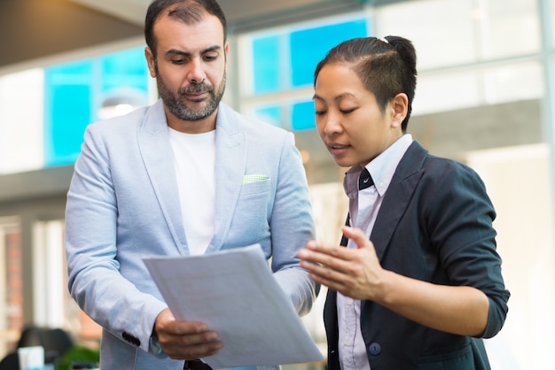 Free photo serious businessman discussing document to asian businesswoman