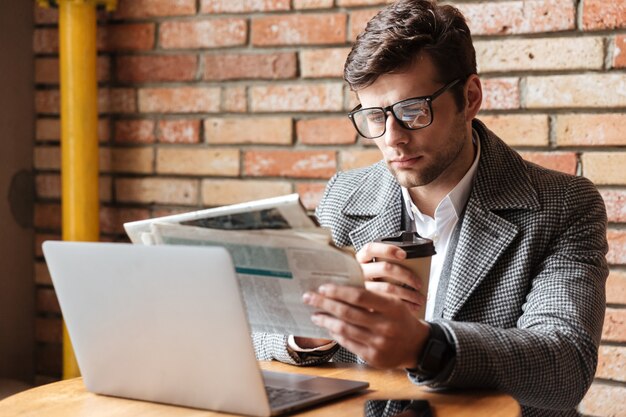 Serious businessman in eyeglasses sitting by table