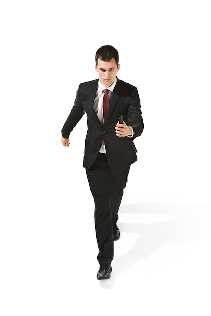 Serious businessman going with mobile phone over white studio background. happy young man in suit. Business, career, success, win concept. Human facial emotions