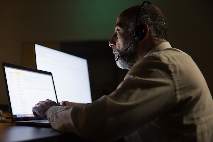 Free Photo serious businessman in headset using laptop