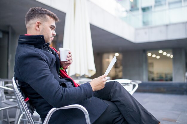 深刻なビジネスマンは、カフェで契約を読んで